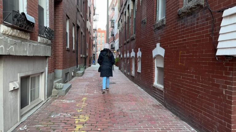 A girl walking down a street in Boston