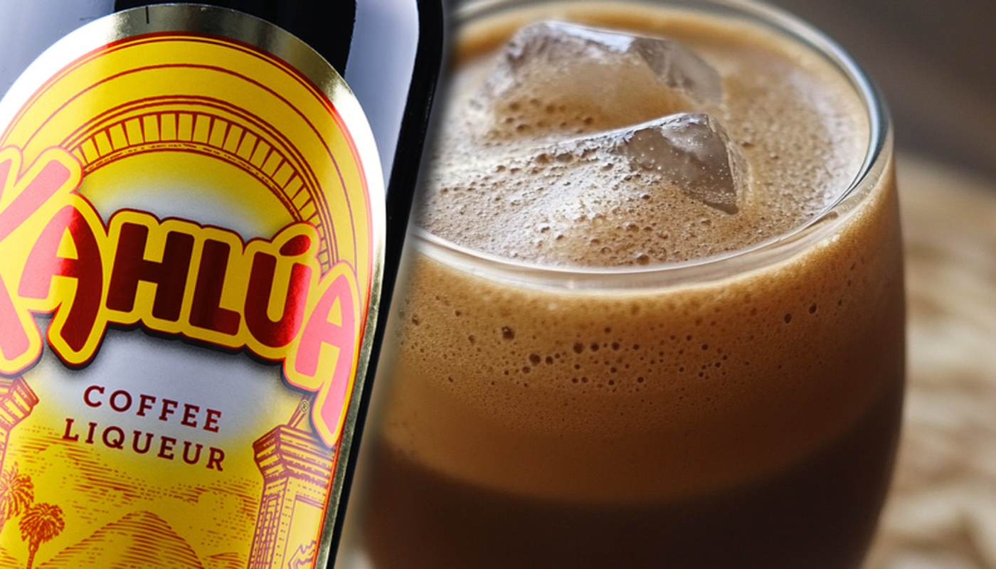 Close-up of a Kahlúa coffee liqueur bottle beside a glass filled with iced coffee