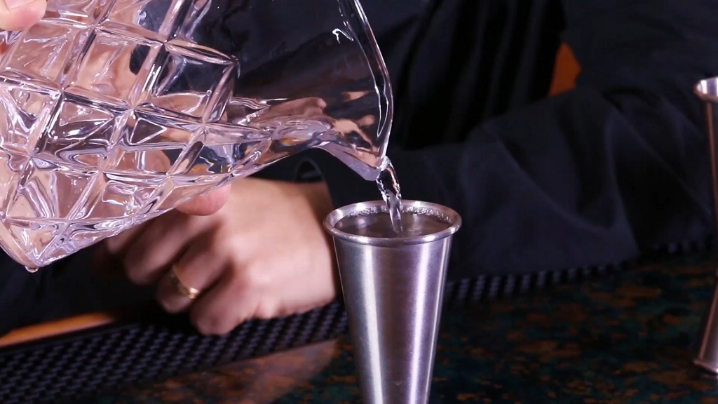 Using a jigger to pour alcohol into a cocktail