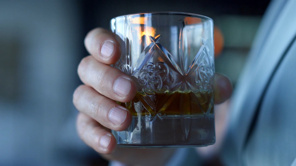 A person holding a glass of whiskey in their hand