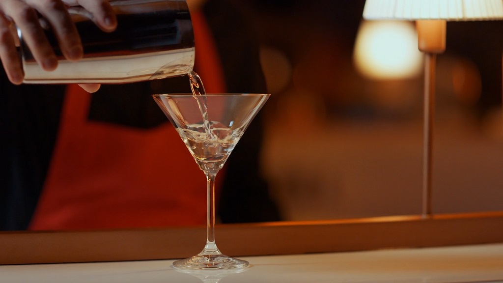 Pouring a cocktail from a shaker into a glass