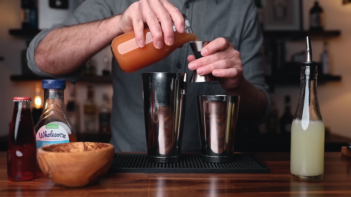 A bartender preparing a refreshing Mocktail by pouring a spiced juice mixture into a cocktail shaker