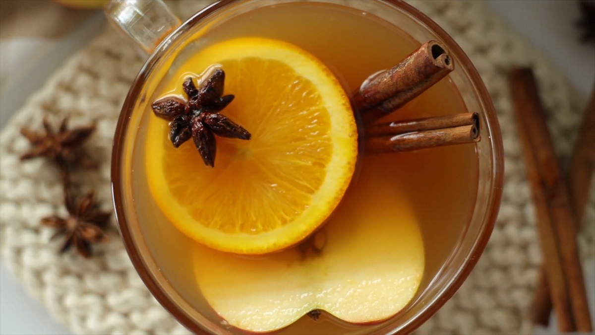 A close-up of a warm spiced apple cider Mocktail with orange slices, cinnamon sticks, and star anise