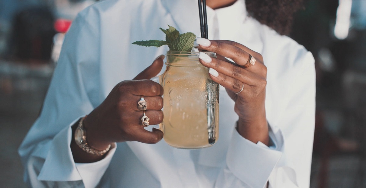 A woman elegantly holding a Mason jar filled with a citrusy Mocktail