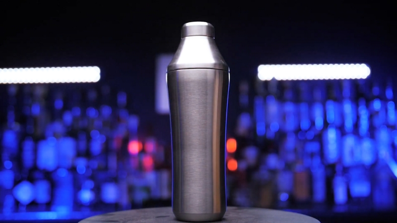 A Sleek Stainless Steel Cocktail Shaker with A Blurred Bar Background