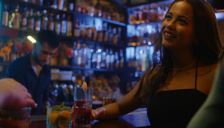 Close-up view of a woman at a bar, enjoying a drink in a dimly lit establishment