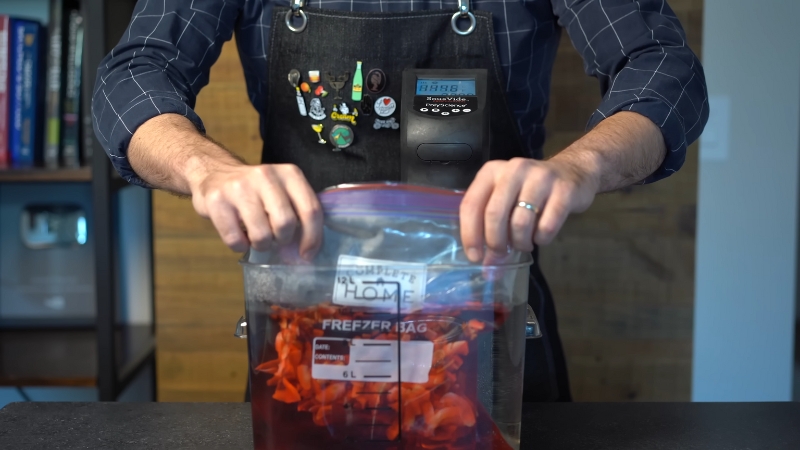 A Person Places a Sealed Bag with Cocktail Ingredients Into a Sous Vide Water Bath for Infusion