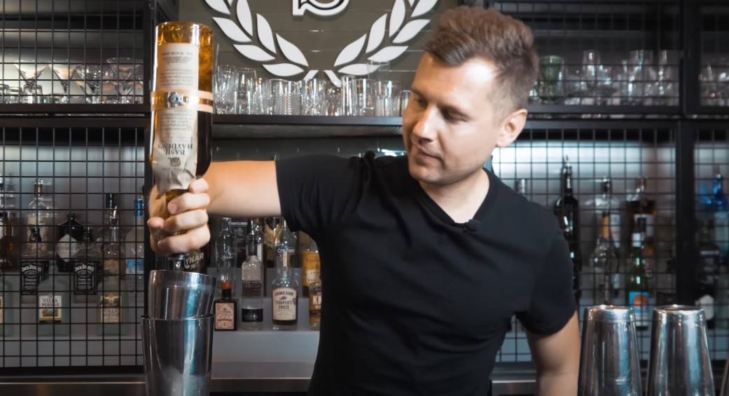 Bartender expertly pours liquor into a mixing glass